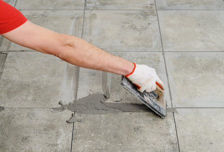 Grouting ceramic tiles. Tilers filling the space between tiles using a rubber trowel.