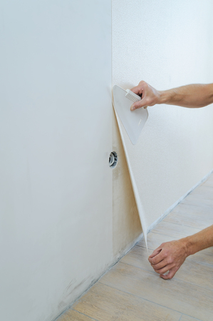 Worker pasting wallpapers. He presses for better adhesion using scraper.の写真素材