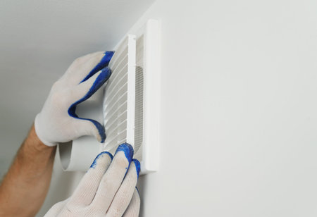 Worker installs ventilation grille on the wall.