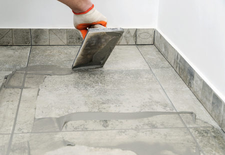 Grouting ceramic tiles. Tilers filling the space between tiles using a rubber trowel.の写真素材