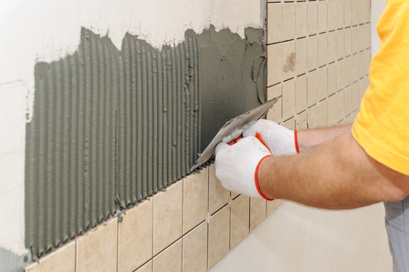 Worker instiling tiles on the wall in the kitchen. He put adhesive using a trowel.の写真素材