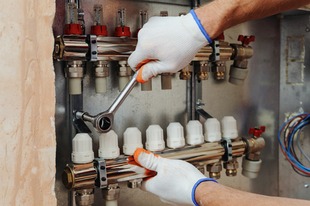 Installation of home heating. A worker fixes the underfloor heating manifold.の写真素材