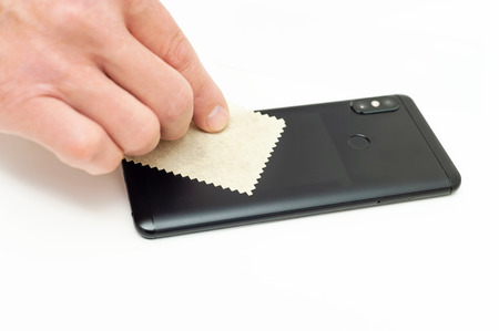A man is wiping the body of the smartphone with a microfiber cloth.の写真素材