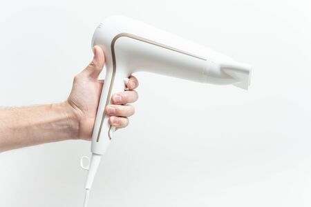 The human hand is holding a hair dryer on a white background.の写真素材