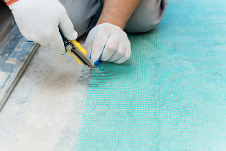 A worker is cutting off a piece of mesh with a knife.