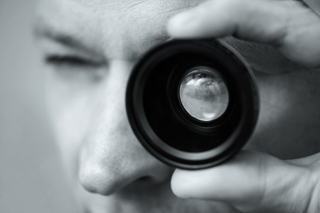 The man is holding and looking through the photo lens.の写真素材