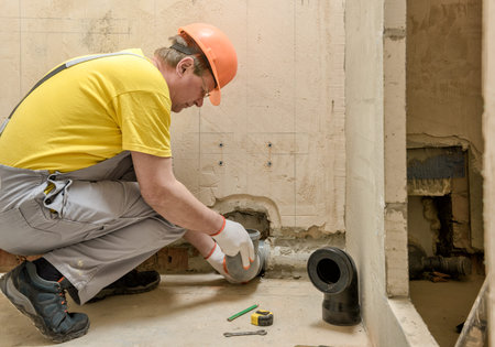 The worker is installing a sewage drain pipe to install the built-in tank of the toilet.