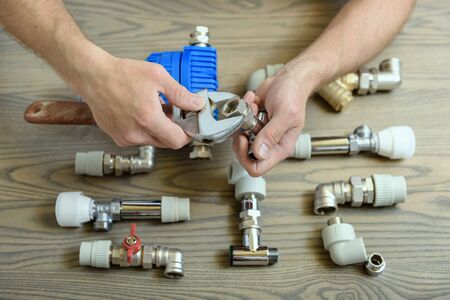 A worker is connecting elements of the plumbing with the adjustable wrenches.の写真素材