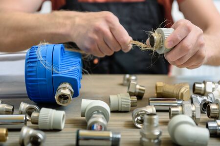 The worker is using a plumber's hemp fibers for sealing up pipe joints.の写真素材