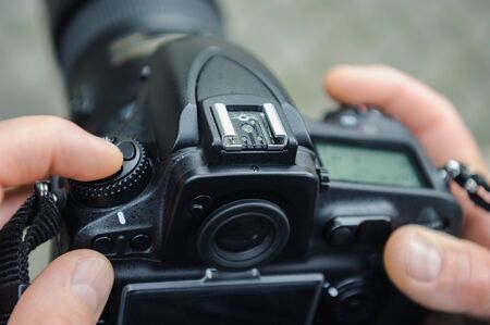A photographer adjusts the camera. The fingers of the photographer are pushing the camera's buttons. Close-upの写真素材