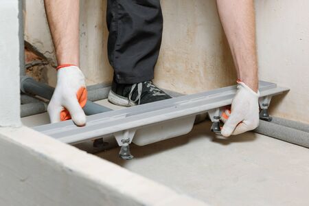 The worker is installing a drain for water in the shower box.の写真素材