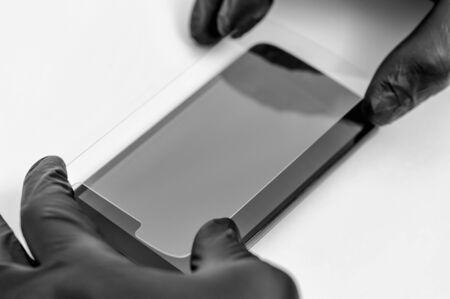 A man is installing a protective glass on the screen of a smartphone.の写真素材