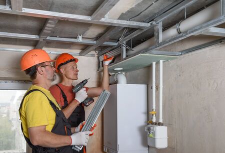Workers are mounting a complex frame for drywall on the ceiling.の写真素材