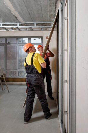 Drywall installation. Workers are mounting a plasterboard to the wall. の写真素材