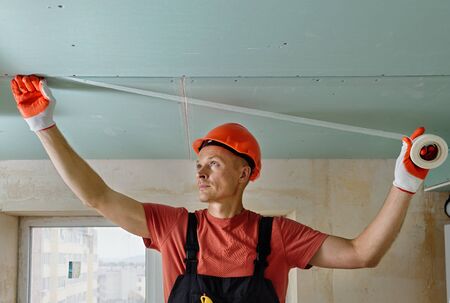 The worker is attaching the mesh to the seams between the plasterboards.の写真素材