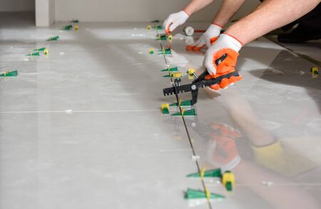 Workers are using plastic clamps and wedges to leveling the large ceramic tile on the floor.の写真素材