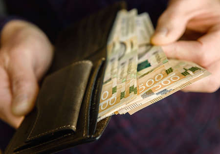 Brown leather wallet with banknotes on an old wooden surface. Close up.の写真素材