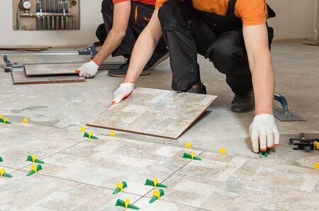 Two workers are installing ceramic tiles on the floor.の写真素材