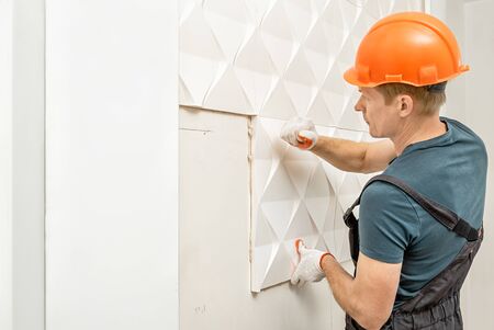 Installation of gypsum 3D panel. The worker is attaching the gypsum tile to the wall.の写真素材