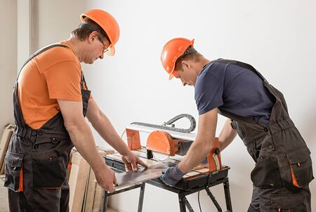 The workers are cutting a ceramic tile on a wet cutter saw  machine.の写真素材