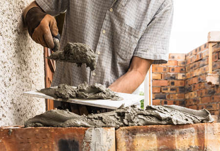 A worker is applying a mortar with a trowel to the brick.の写真素材