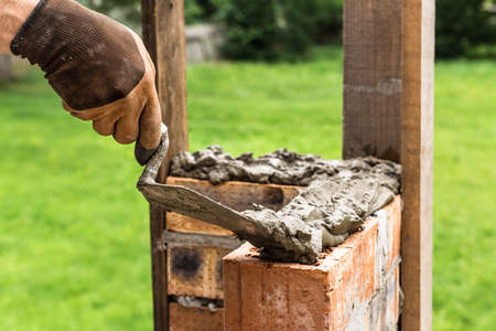 A worker is applying a mortar with a trowel to the brick.の写真素材