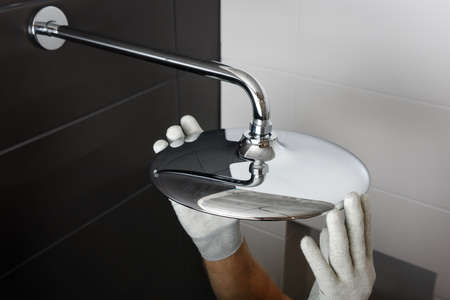 The worker's hands install the head of the built-in shower faucet.の写真素材
