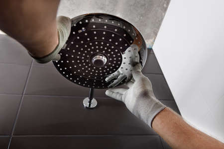 The worker's hands install the head of the built-in shower faucet.の写真素材