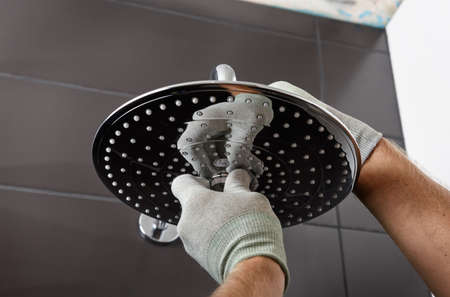 The worker's hands install the head of the built-in shower faucet.の写真素材
