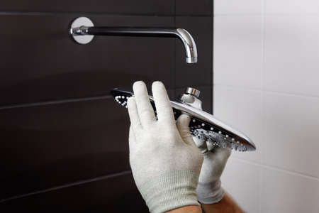 The worker's hands install the head of the built-in shower faucet.の写真素材