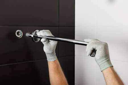 The worker's hands install the tube of the built-in shower faucet.の写真素材