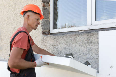 Insulation of the house with polyfoam. The worker is checking with the construction level the accuracy of the installation of polystyrene board on the facade.の写真素材