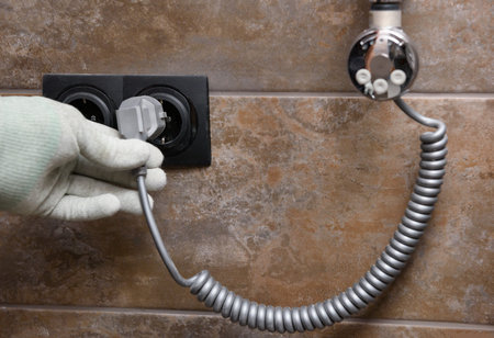 A worker is installing a heating element in the towel warmer in the bathroom.