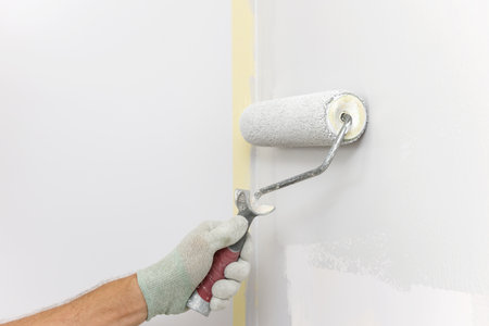A painter is painting a wall in a room with a roller.の写真素材
