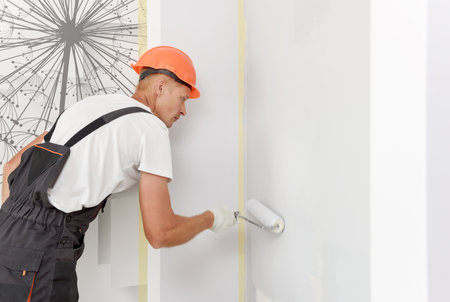 The painter is painting a wall in a room with a roller.の写真素材
