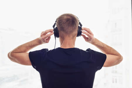 The man in headphones on the background of the window. Back view.の写真素材