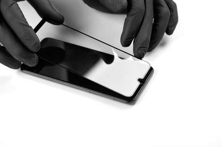 A man is installing a protective glass on the screen of a smartphone.の写真素材