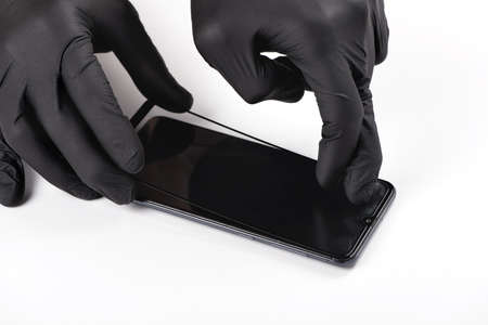 A man is installing a protective glass on the screen of a smartphone.の写真素材
