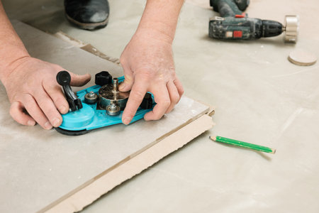 A tiler uses a caliper with a suction cup to drill holes in the ceramic tile.