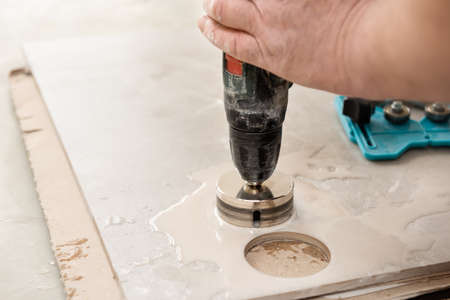 A tiler is using a diamond crown to drill holes in the ceramic tile.の写真素材
