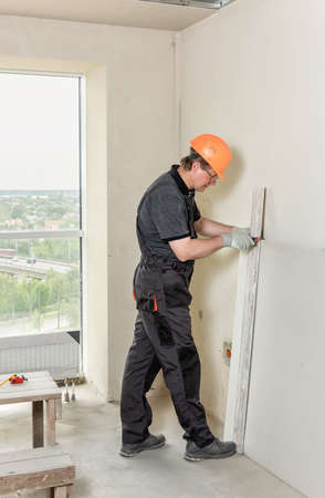 Installation of drywall. The worker is cutting off a piece of drywall.の写真素材