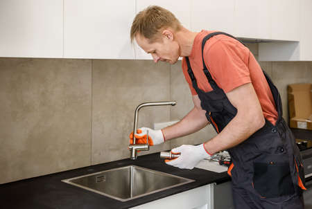 The plumber is installing a faucet on the kitchen sink.の写真素材