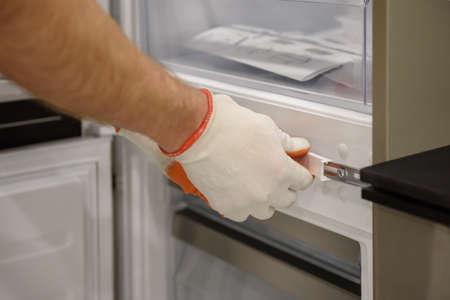 A worker is fixing the built-in refrigerator in the kitchen furniture.の写真素材