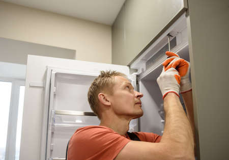 The worker is fixing the built-in refrigerator in the kitchen furniture.の写真素材