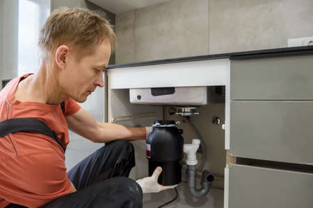 The worker is installing a household waste shredder for the kitchen sink.の写真素材