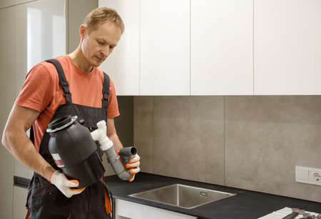 The worker is installing a household waste shredder for the kitchen sink.の写真素材