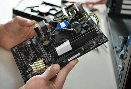 A technician is holding the motherboard in a desktop case.の写真素材