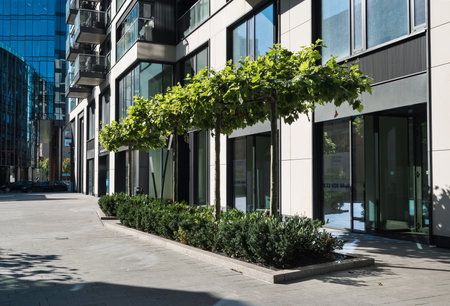 The lawn with bushes and trees in front of a residential building.の写真素材