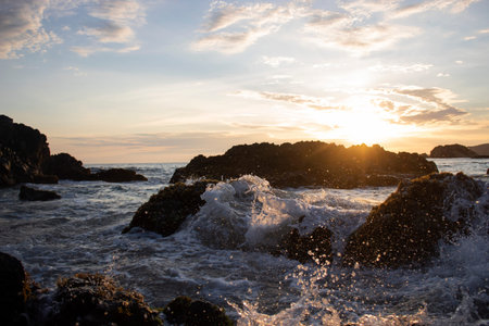 Waves crashing on the rocks at the shore of the beach during sunset