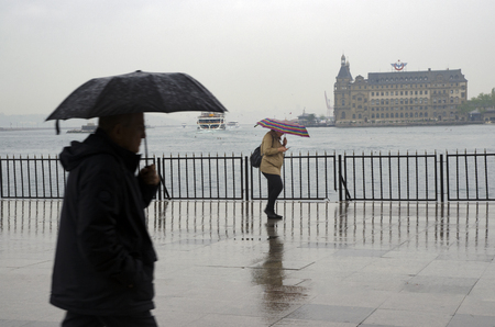 Istanbul, Turkey - April 18, 2014: Istanbul Kadikoy Steamboat pier and Haydarpasa train station building.
 People walking in the rain pier. Strait of Istanbul, Kadikoy Pier, ferries are the most popular form of public transport in Istanbul for.のeditorial素材